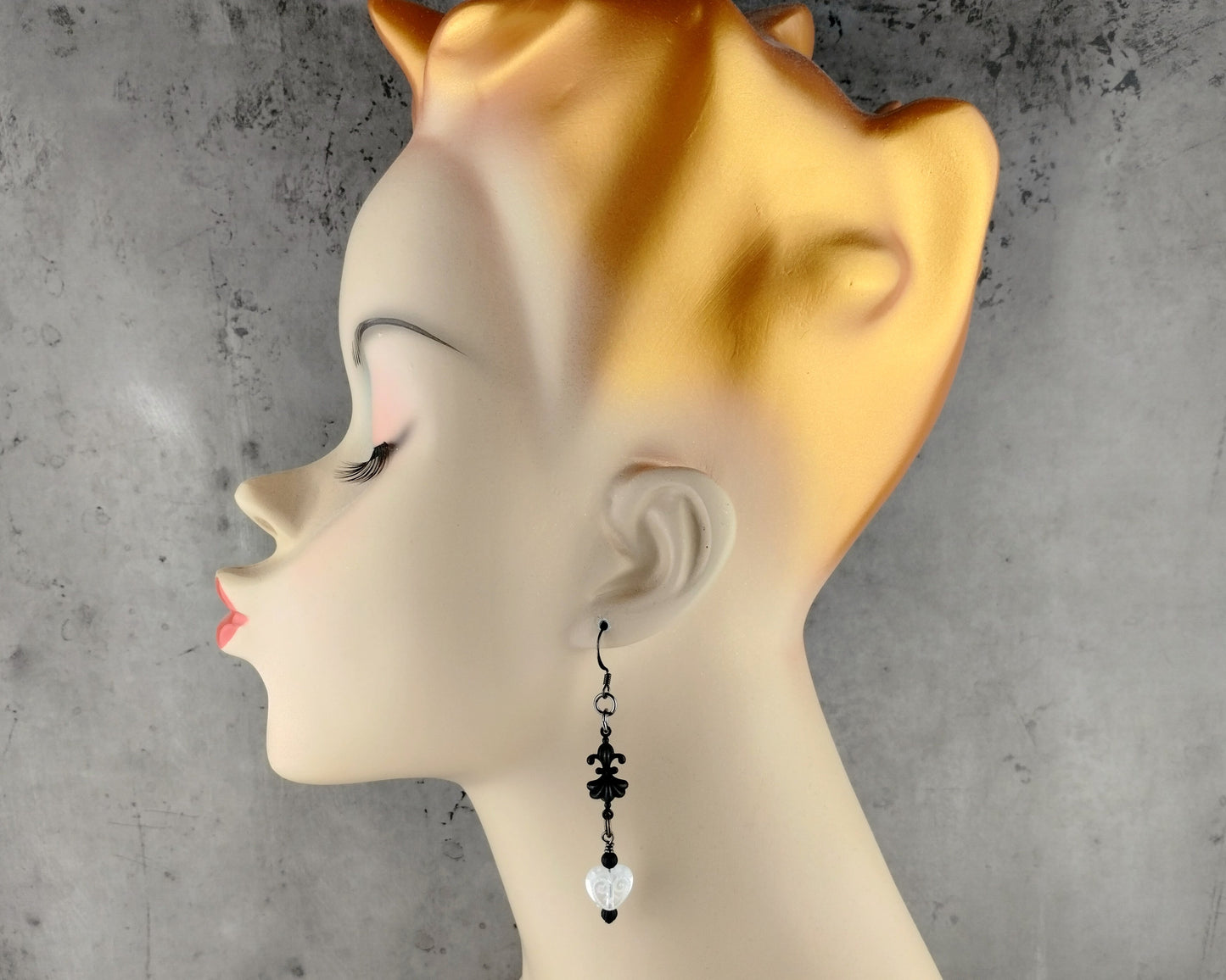 Mannequin head with a decorative earring on a gray background