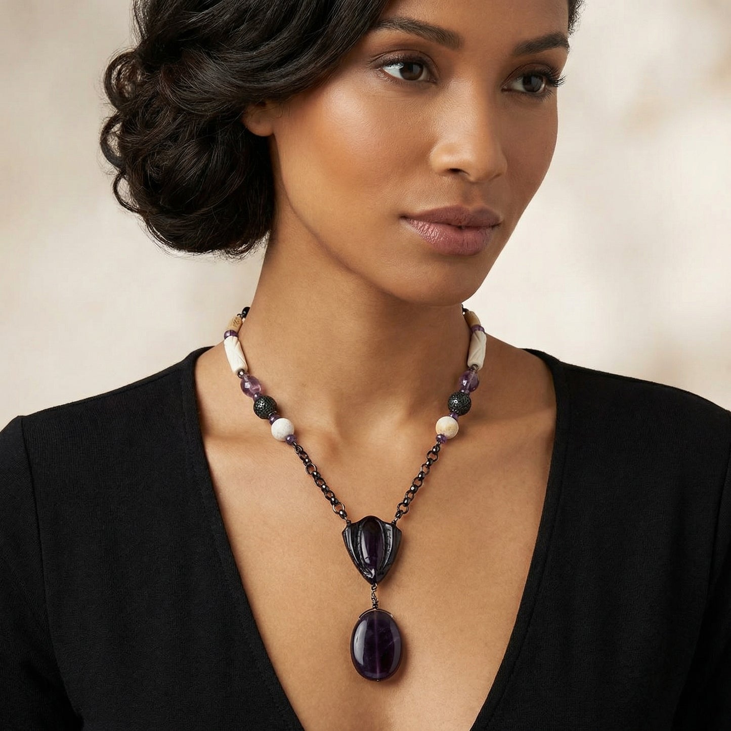 Woman wearing a necklace with a large purple pendant against a neutral background