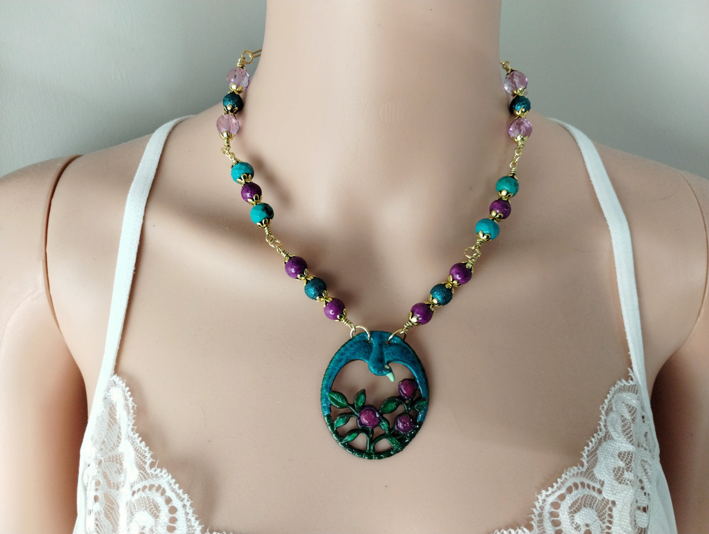 Necklace with a blue pendant on a mannequin wearing a white lace top.