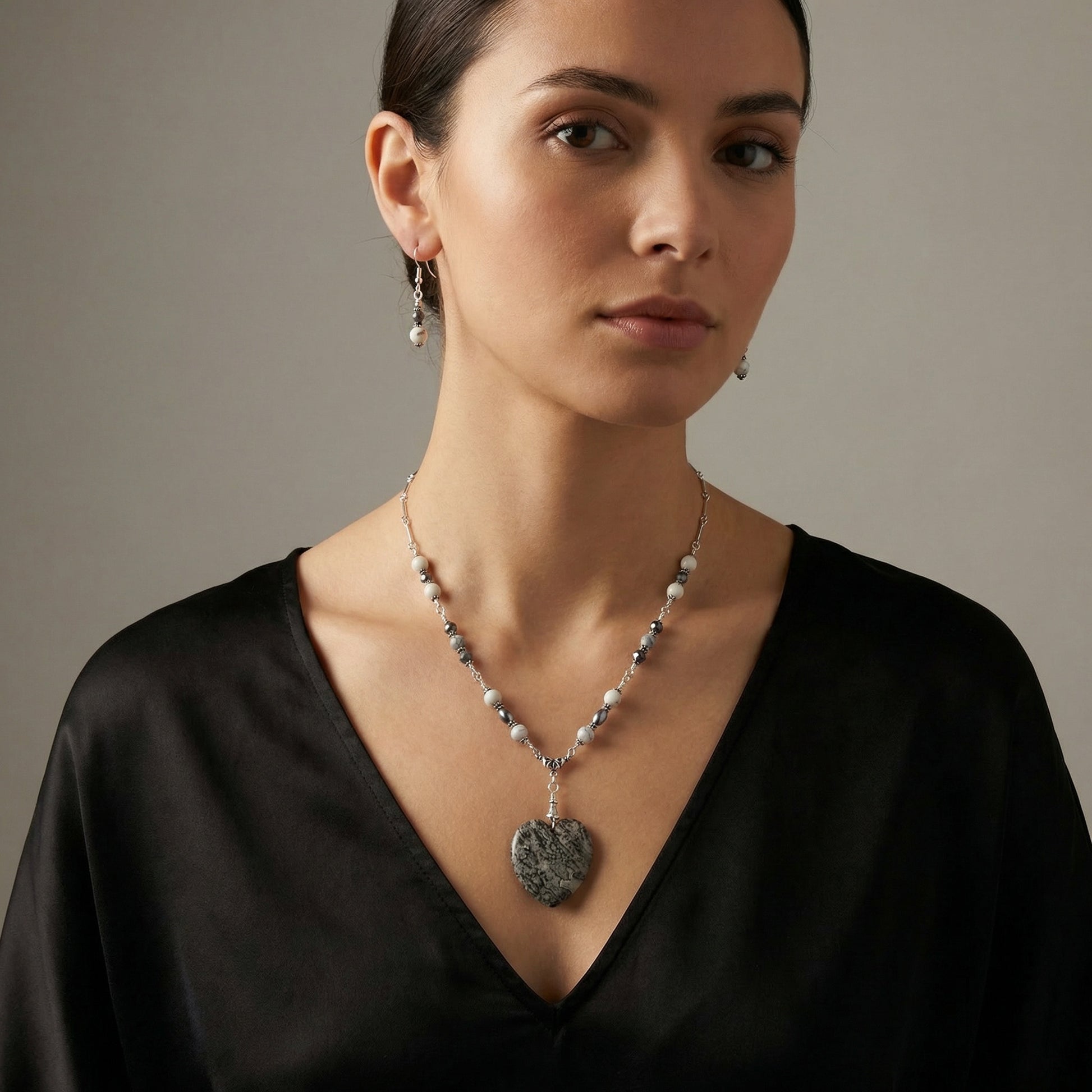 Woman wearing a necklace with a pendant against a neutral background