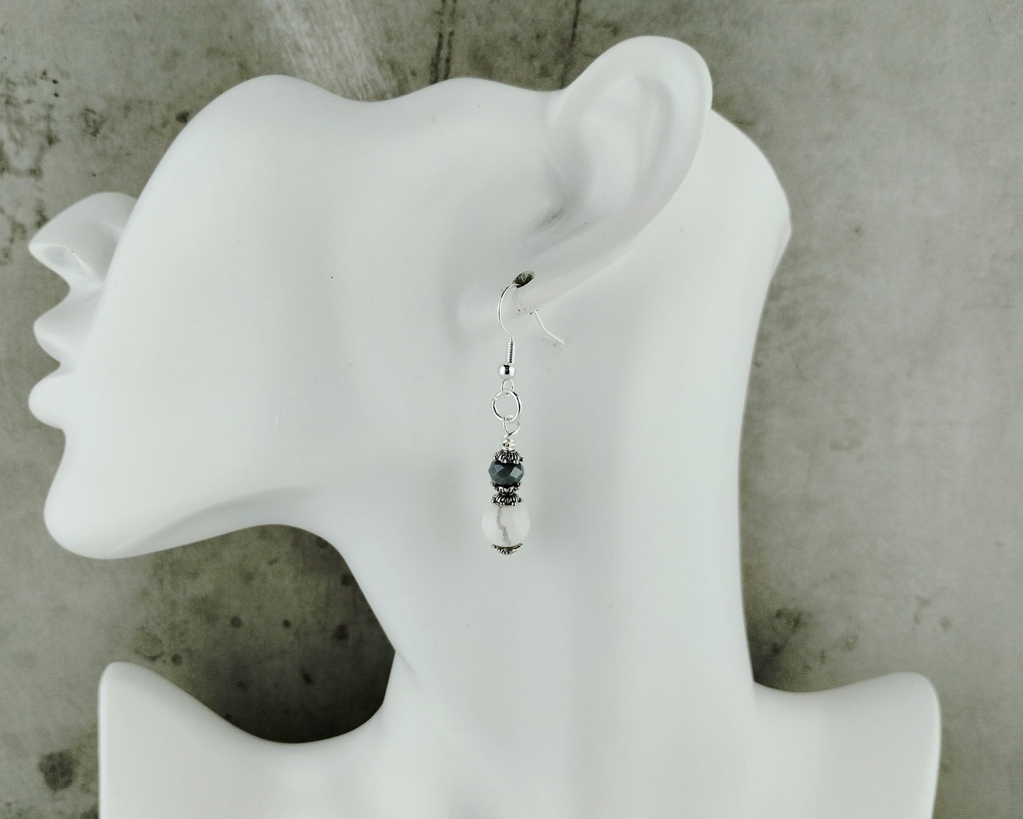 Earring displayed on a white mannequin ear against a gray background
