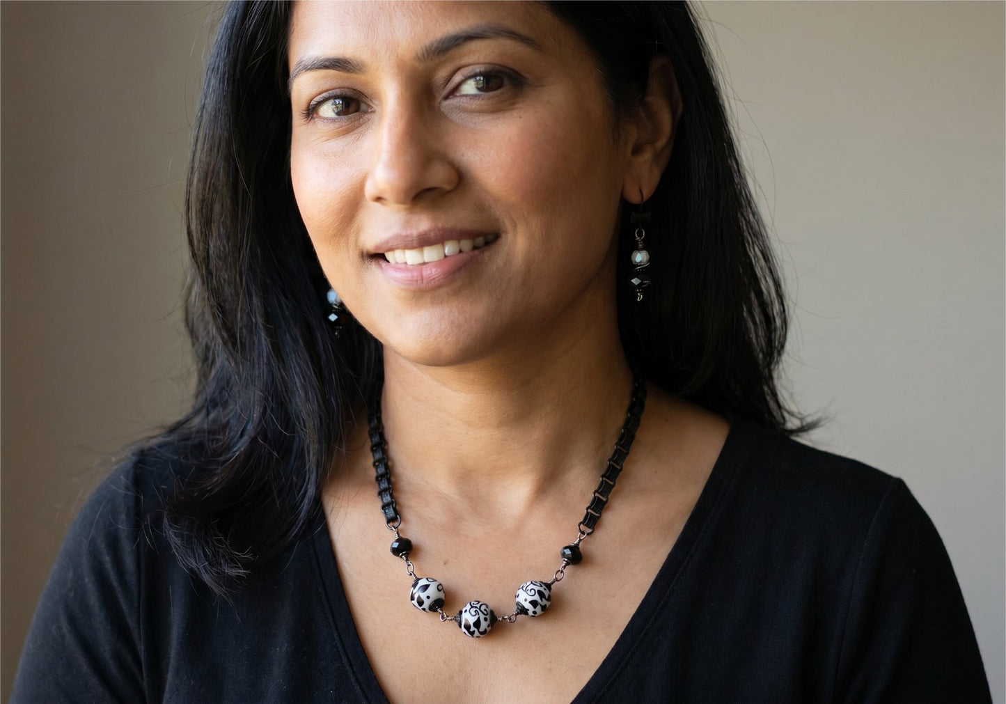 Woman wearing a black top and a necklace with a blurred background